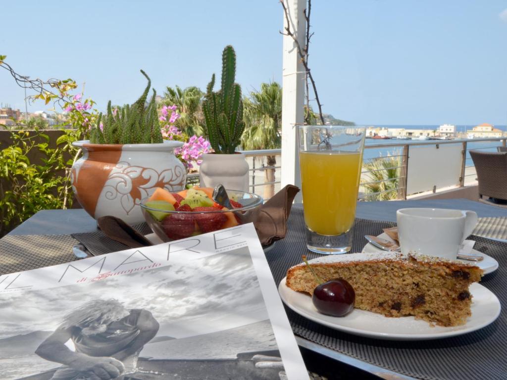 a table with a plate of cake and a glass of orange juice at Hotel La Bussola in Milazzo