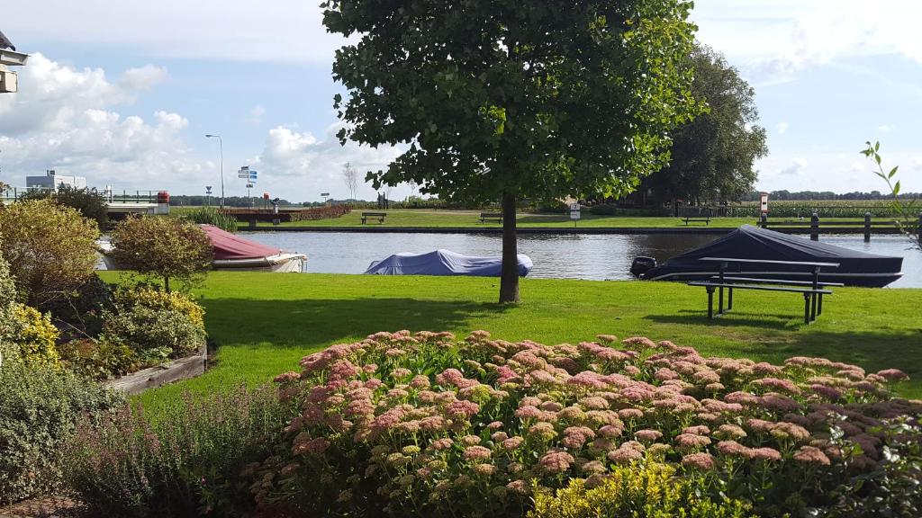 a park with a picnic table and a boat on the water at Vakantiehuis de wilgenhof in Wetering