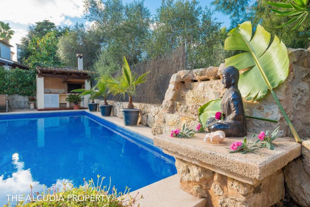 a statue sitting next to a swimming pool at VILLA CAN JAUME in Alcudia