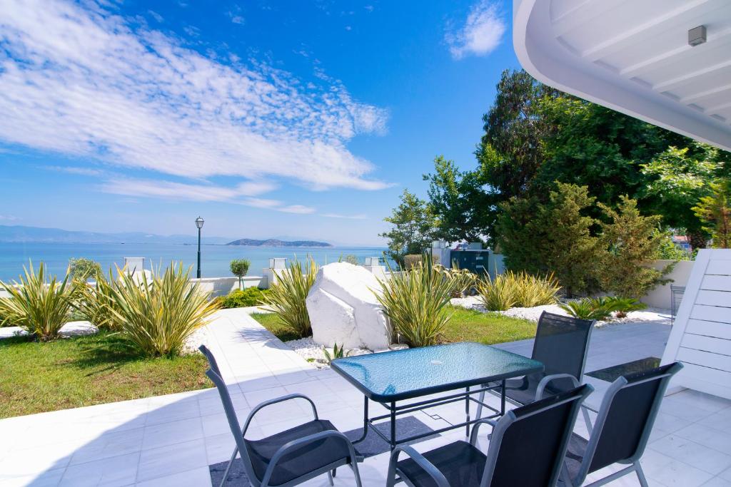 um pátio com uma mesa e cadeiras e o oceano em Mythodea Apartments em Limenas