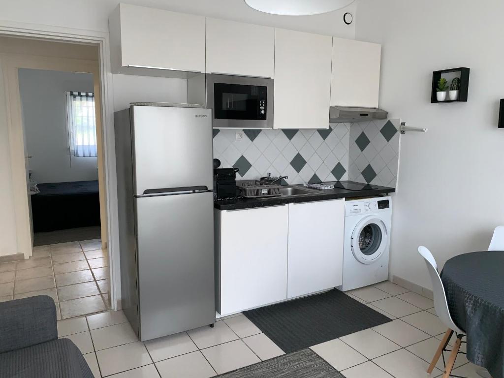 a kitchen with a refrigerator and a washing machine at Appartement des Tilleuls RDC in Royan