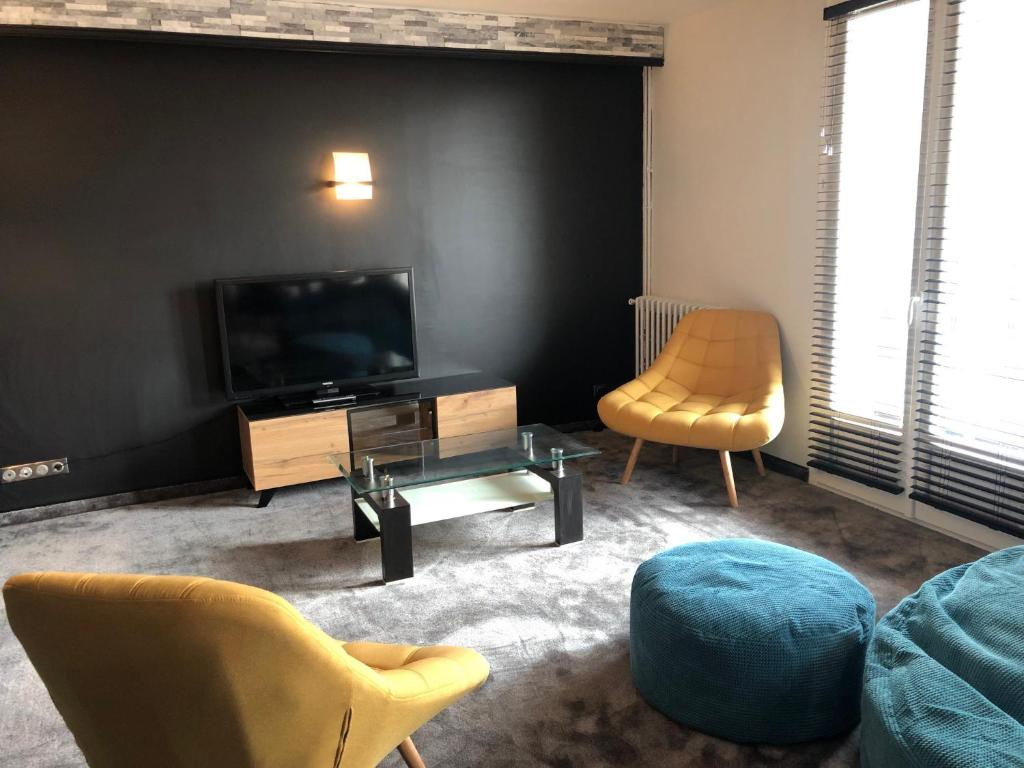 a living room with a tv and a chair at Logis Chez Camillou in Aumont-Aubrac