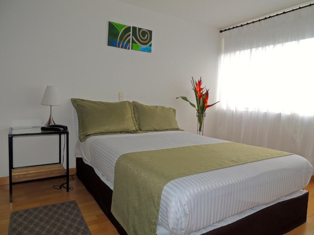 een slaapkamer met een bed met een vaas met bloemen erop bij Hotel Portal de Milán in Manizales