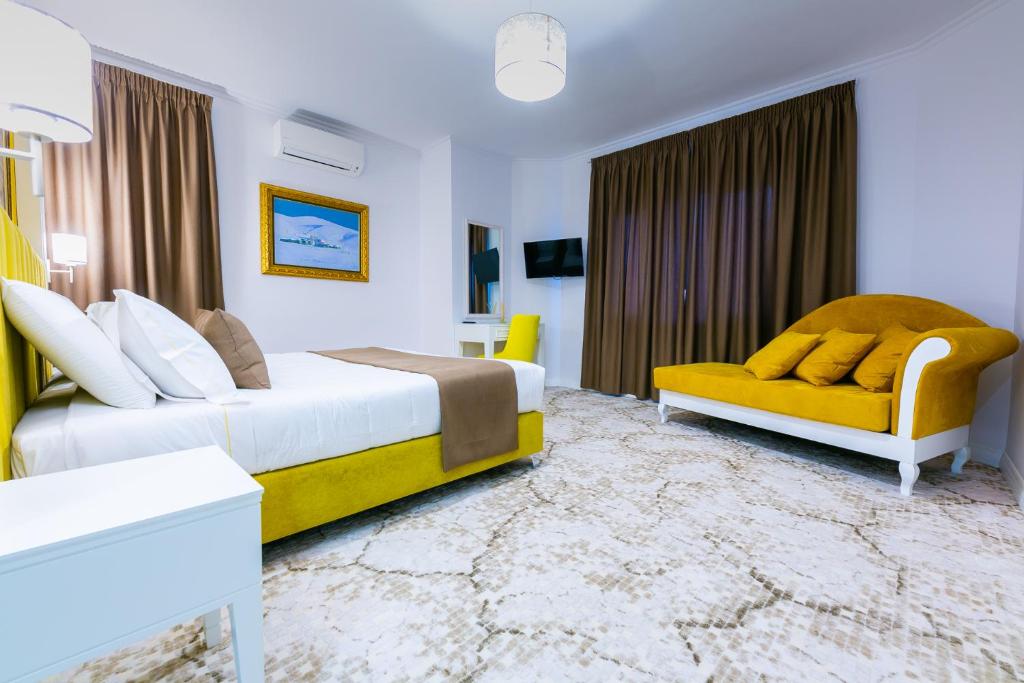 a hotel room with two beds and a yellow couch at ART Hotel Tirana in Tirana