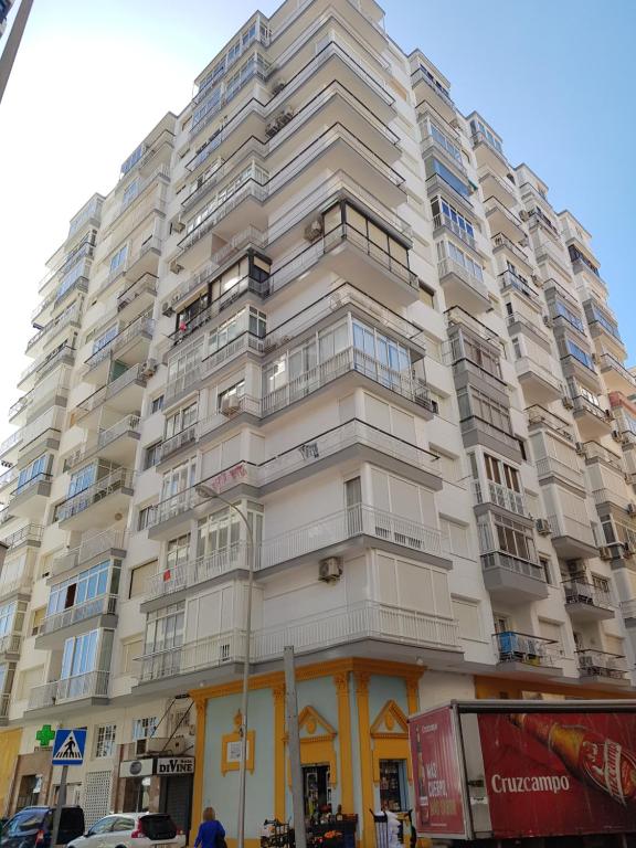 a tall white building with windows on a street at Apartamento Málaga Port in Málaga