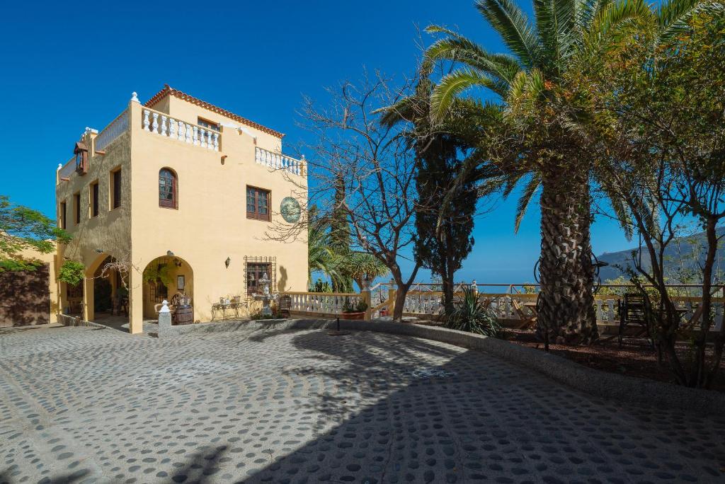 een gebouw met een palmboom naast een weg bij Hotel Rural Villa Ariadna in Güimar