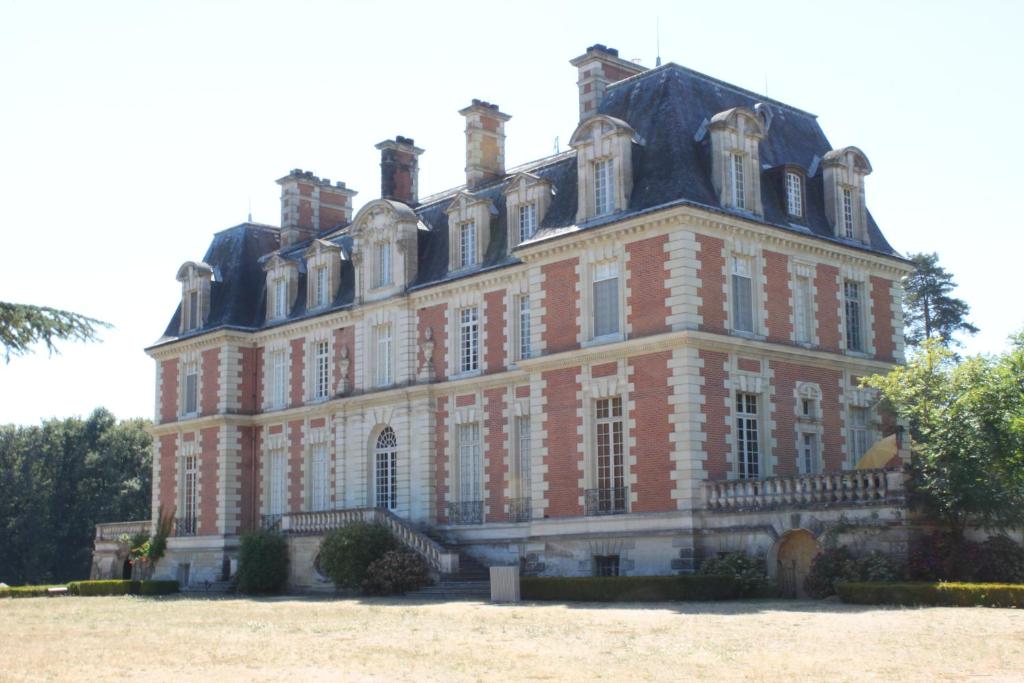 ein großes rotes Backsteingebäude mit einem großen Fenster in der Unterkunft Chateau du Guérinet D'Orchaise in Orchaise