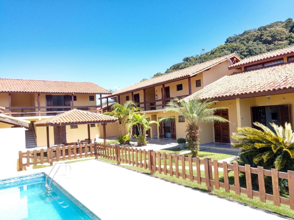 a villa with a swimming pool and a resort at Chalés Flamboyant in Caraguatatuba