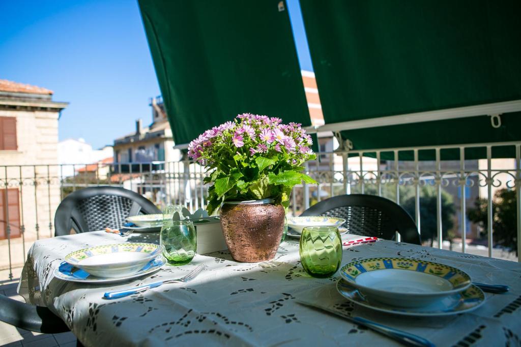 une table avec des assiettes et un vase avec des fleurs. dans l'établissement Appartamento Antonella a due passi dal centro e dal mare, à Grottammare