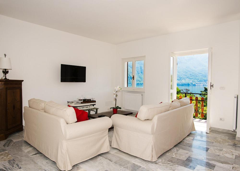 a living room with two white couches and a television at Casa Sissi in Bellagio