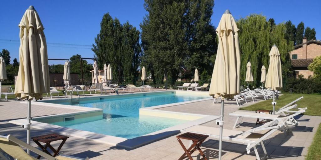 einen Pool mit Stühlen und Sonnenschirmen in der Unterkunft Agriturismo I Bosconi in Cesena