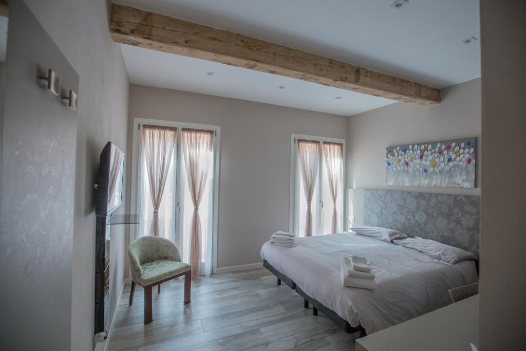 Schlafzimmer mit einem Bett, einem Stuhl und Fenstern in der Unterkunft Lanterna Room&Breakfast in Carpi