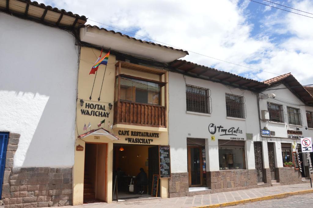 a white building with a sign for a store at Hostal Wasichay in Cusco