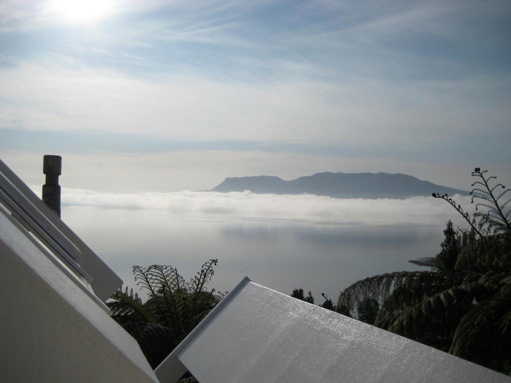 uma vista para o oceano com nuvens no céu em te Whare -Lake Tarawera tree-top nest em Lake Tarawera