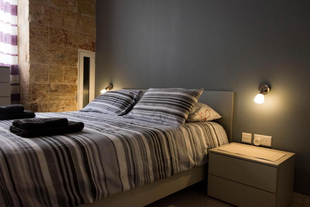 ein Schlafzimmer mit einem großen Bett mit gestreifter Bettwäsche in der Unterkunft Great Siege Apartment in Senglea