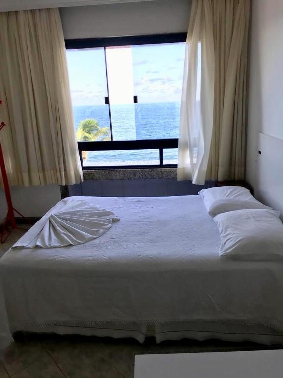 a bedroom with a bed with a view of the ocean at Flat Vista Mar Frente ou Lateral na Barra em Salvador in Salvador