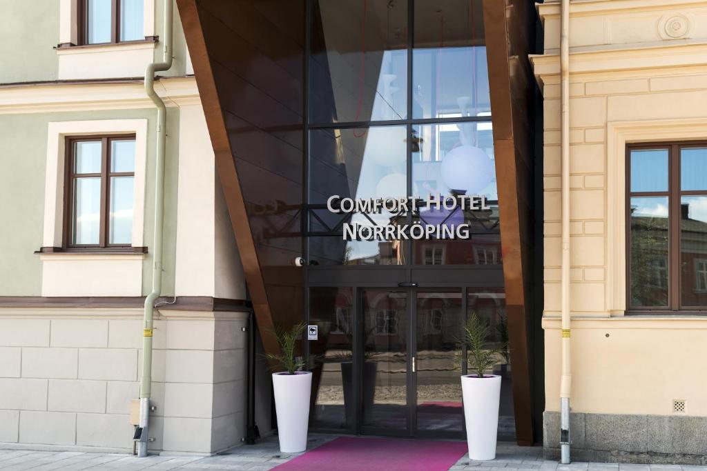 uma porta de vidro para um edifício com dois vasos de plantas na frente em Comfort Hotel Norrköping em Norrköping