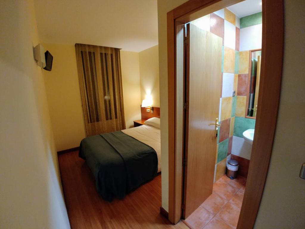 Habitación pequeña con cama y baño. en Hostal Prada Borges en León