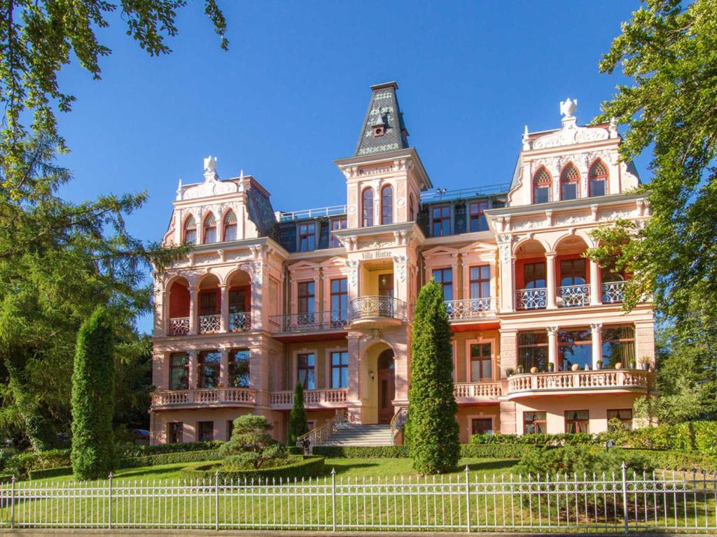 un gran edificio rosa con árboles delante de él en Villa Hintze Wohnung 9, en Heringsdorf