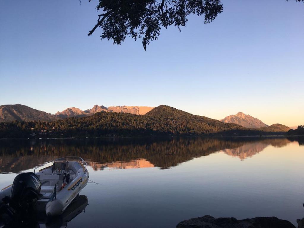 un barco sentado en un lago con montañas en el fondo en Albanta casa con costa en Bariloche en San Carlos de Bariloche