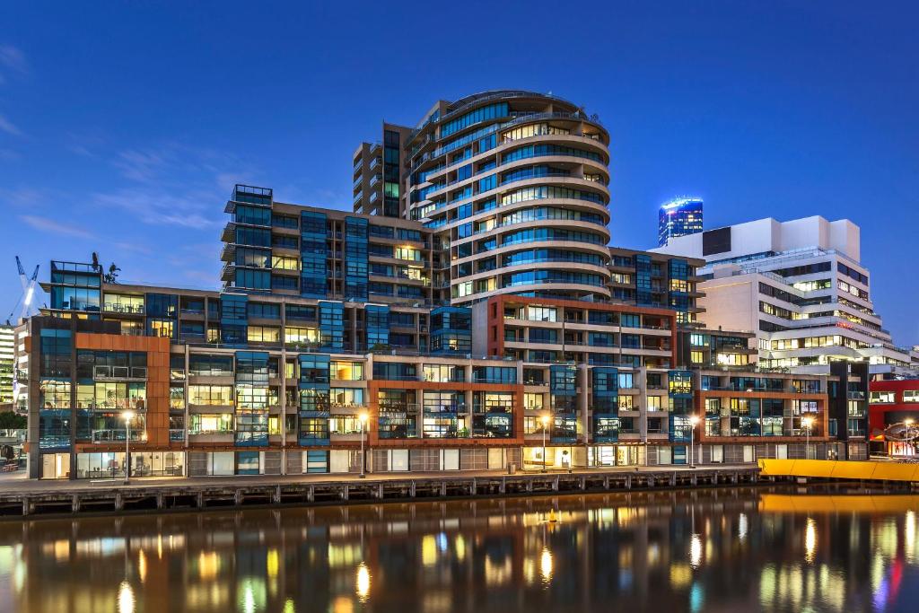 grupa wysokich budynków obok zbiornika wodnego w obiekcie Waterfront Melbourne Apartments w Melbourne