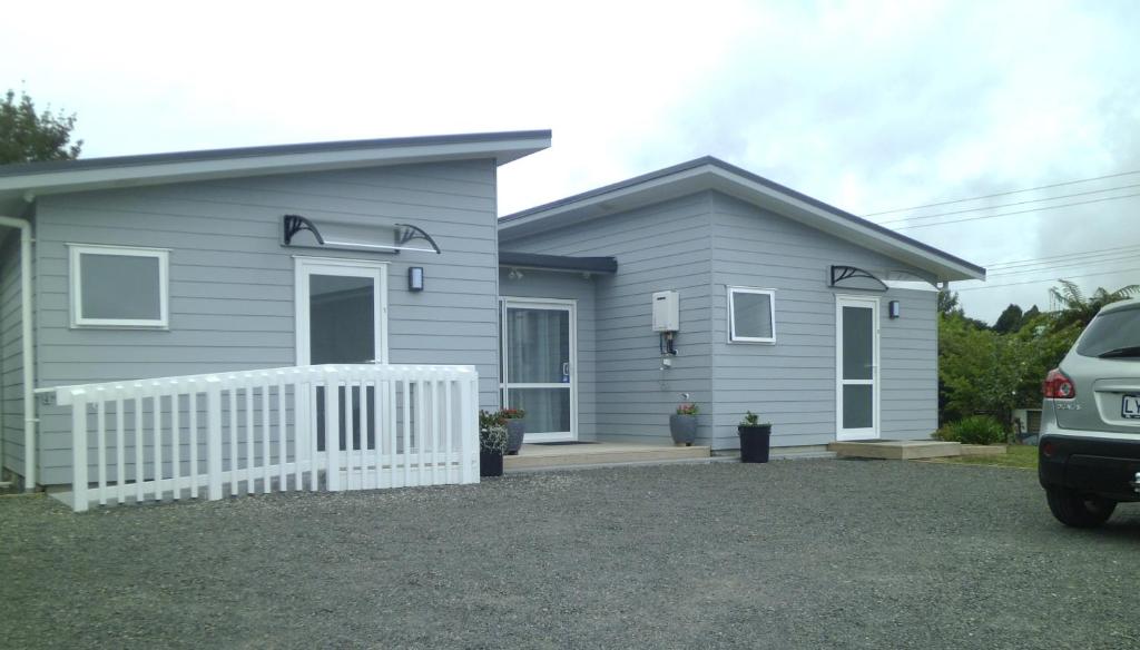 ein graues Haus mit einem weißen Zaun davor in der Unterkunft Trailblazer Studios in Waihi