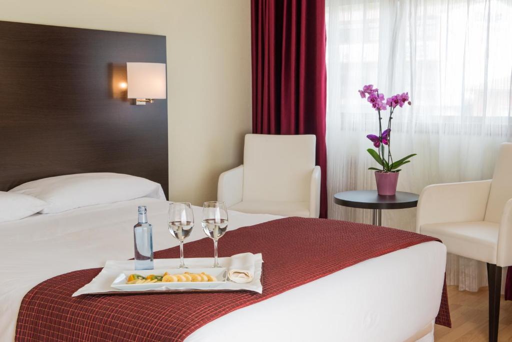 Habitación de hotel con cama y bandeja de comida y copas de vino en Hotel Santiago Apóstol, en Santiago de Compostela