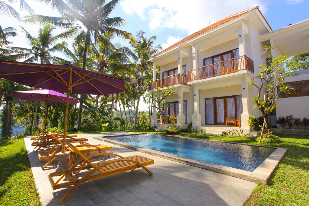 une villa avec une piscine dotée de chaises et de parasols dans l'établissement Suarsena Villa Ubud, à Ubud