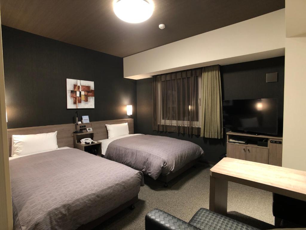 a hotel room with two beds and a television at Hotel Route-Inn Tokoname Ekimae in Tokoname