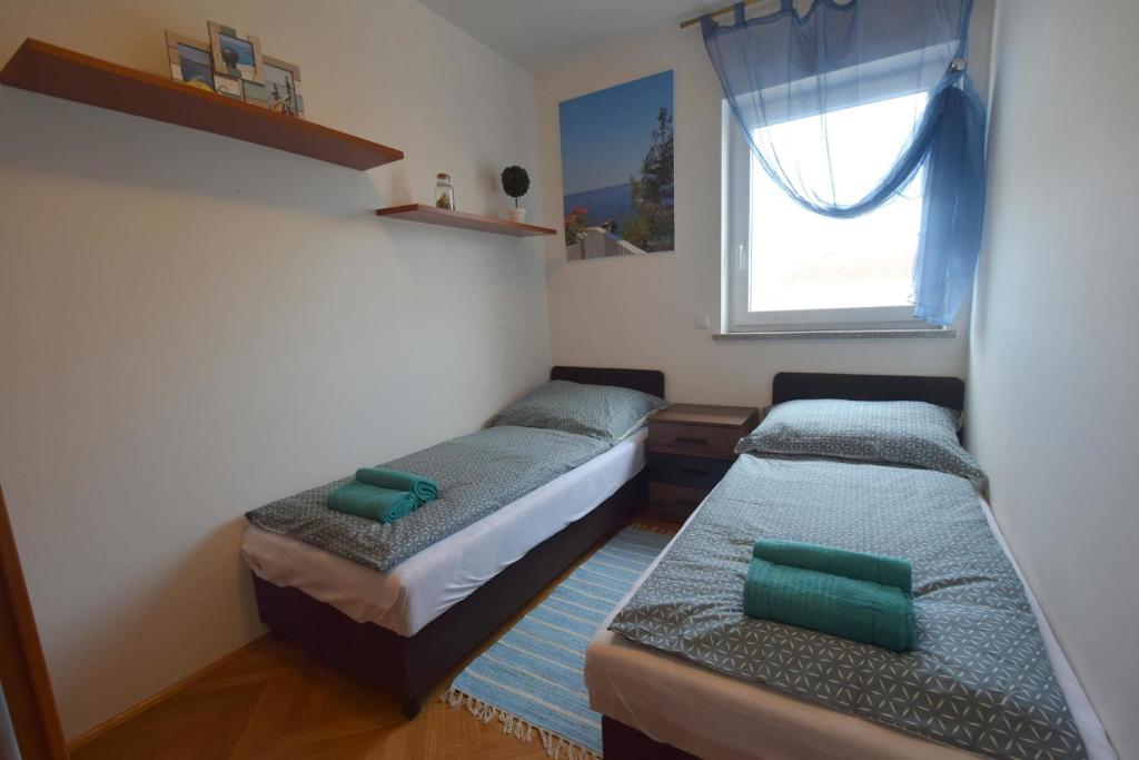 2 łóżka w małym pokoju z oknem w obiekcie Apartment Adlitika w mieście Malinska