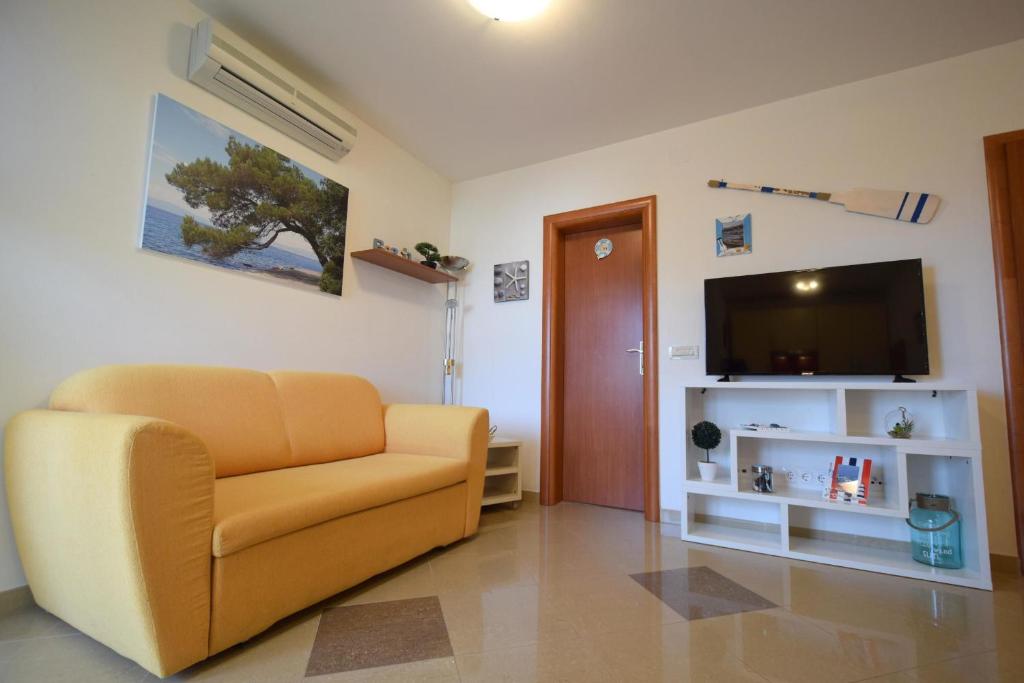 salon z kanapą i telewizorem z płaskim ekranem w obiekcie Apartment Adlitika w mieście Malinska