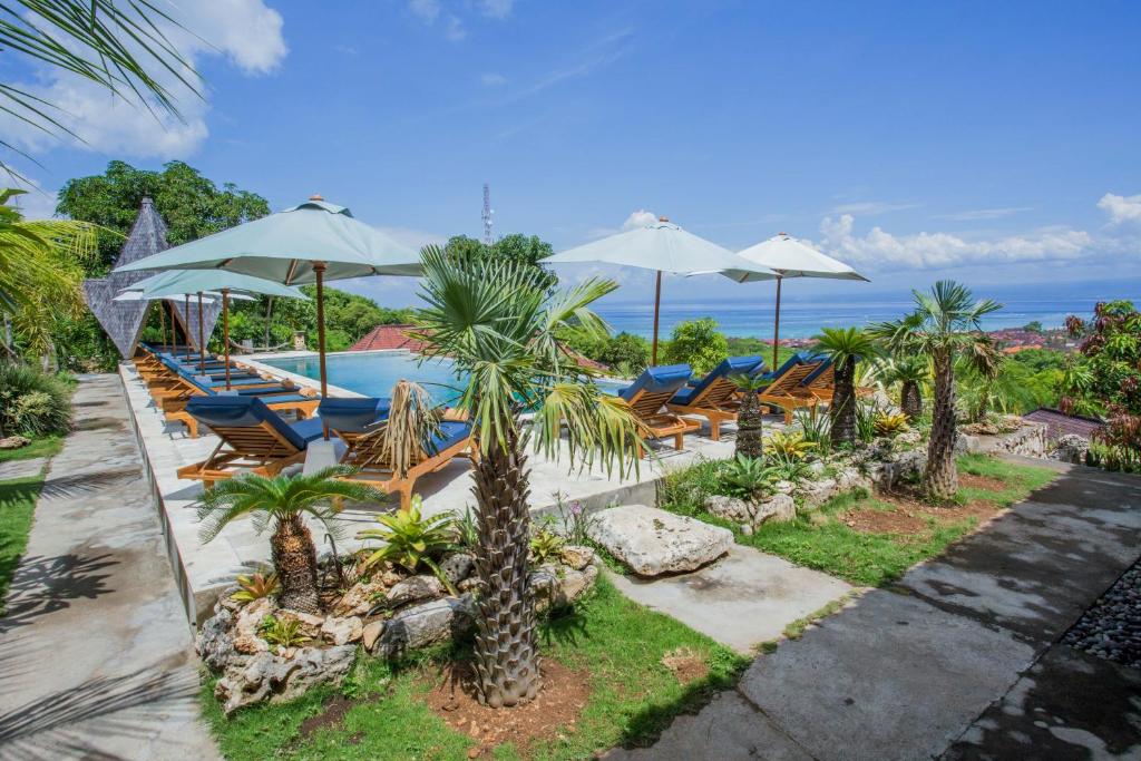 a resort with a pool and chairs and umbrellas at Bukit Taman Cottages in Nusa Lembongan