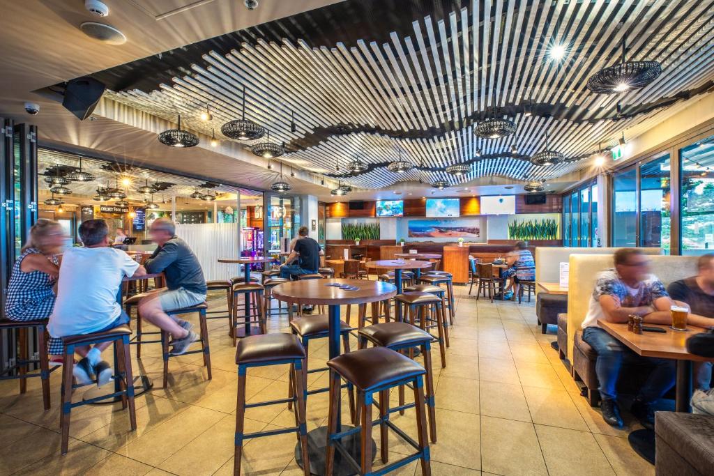 a group of people sitting at tables in a restaurant at Narrabeen Sands Hotel by Nightcap Plus in Narrabeen