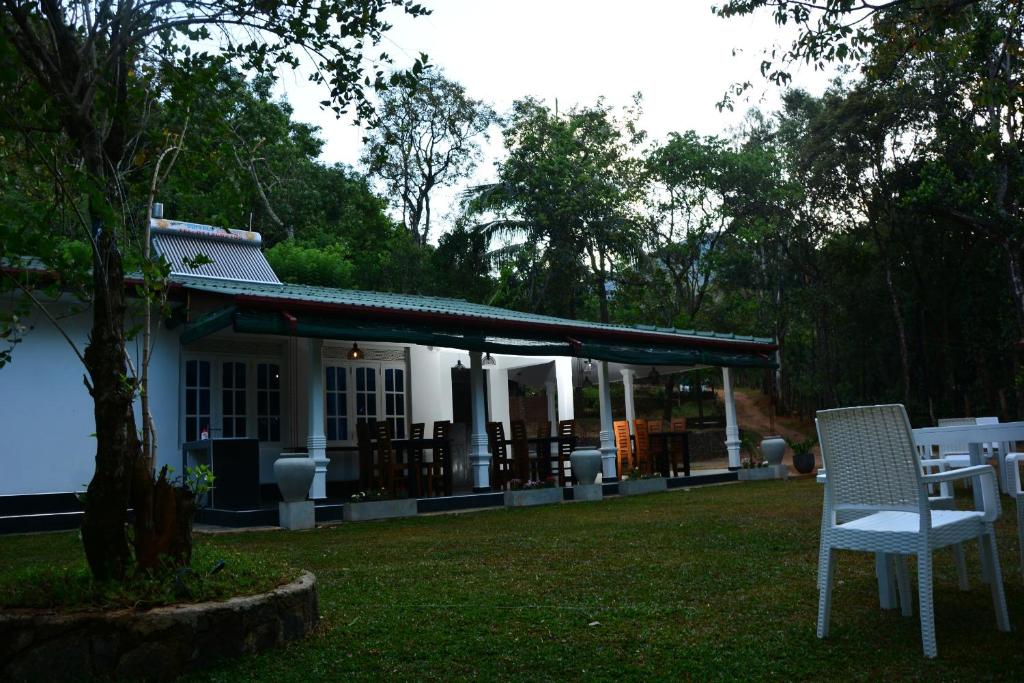 a white house with a table and a chair in the yard at Eagle Wings Holiday in Belihul Oya