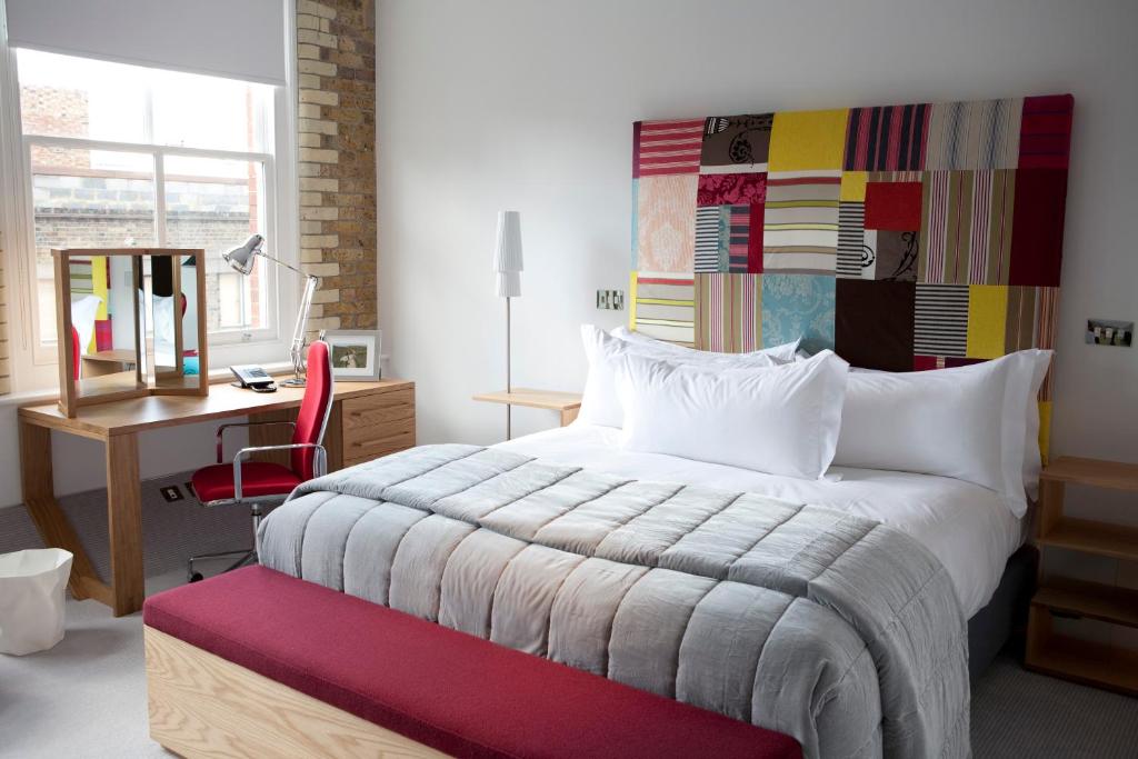 1 dormitorio con cama, escritorio y silla en Boundary Shoreditch, en Londres