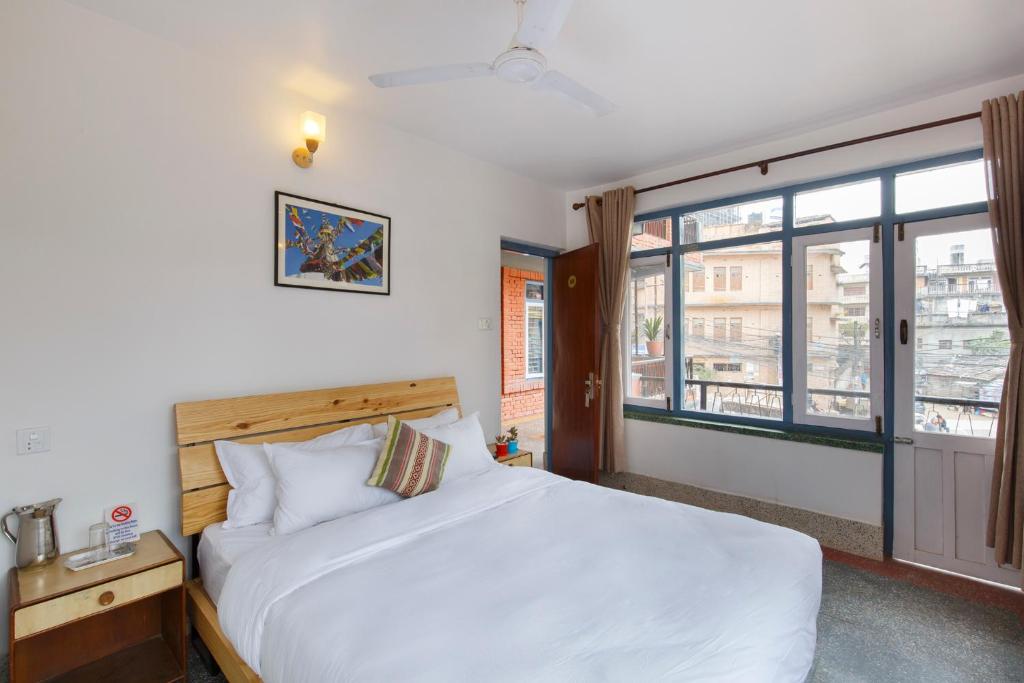 una camera da letto con un grande letto bianco e una finestra di Pacific Guest House a Kathmandu