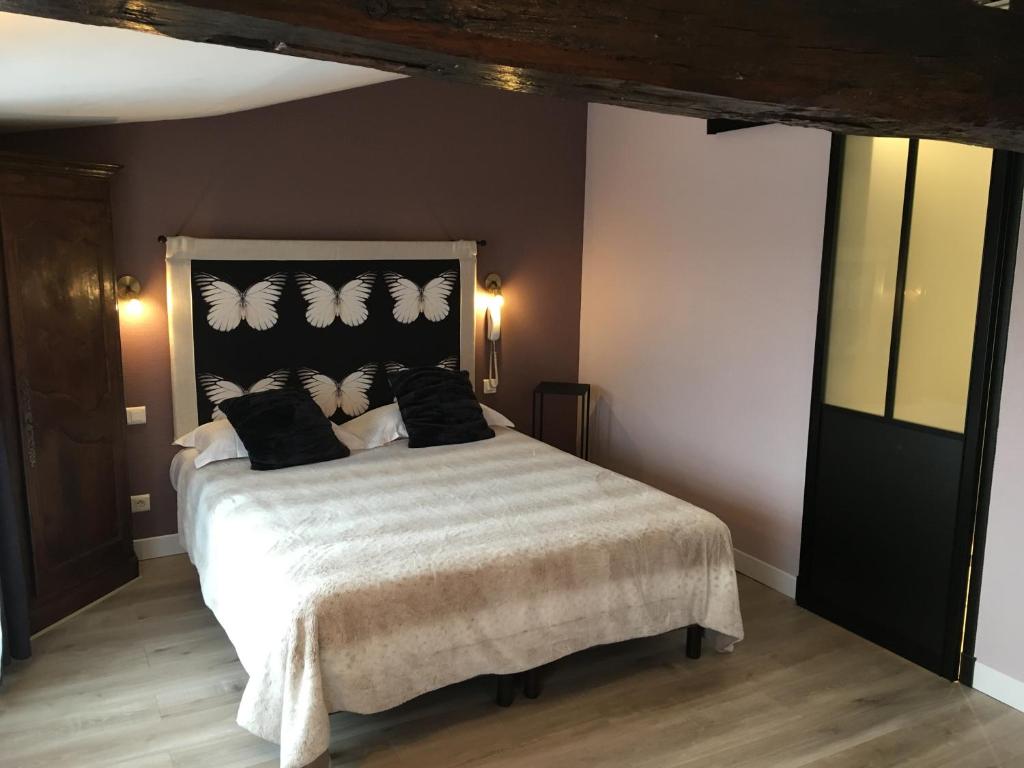 sypialnia z dużym łóżkiem z czarnym zagłówkiem w obiekcie Logis Hôtel Le Moulin de Chalons w mieście Le Gua