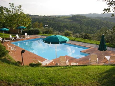ein großer Pool mit Stühlen und einem Sonnenschirm in der Unterkunft Il Casalone in Impruneta