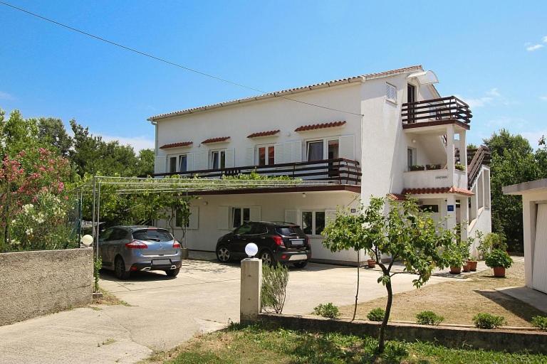 a white house with two cars parked in a parking lot at APARTMAN KATY in Šilo