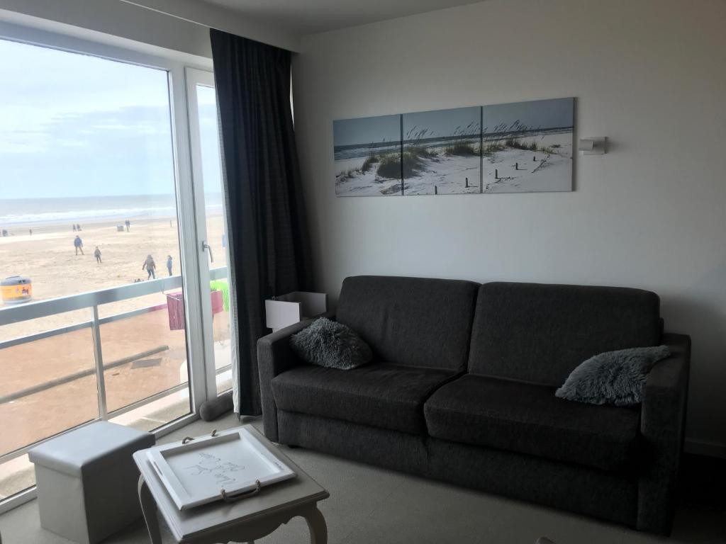 - un salon avec un canapé et une vue sur la plage dans l&#39;établissement 50 Zeedijk, à La Panne