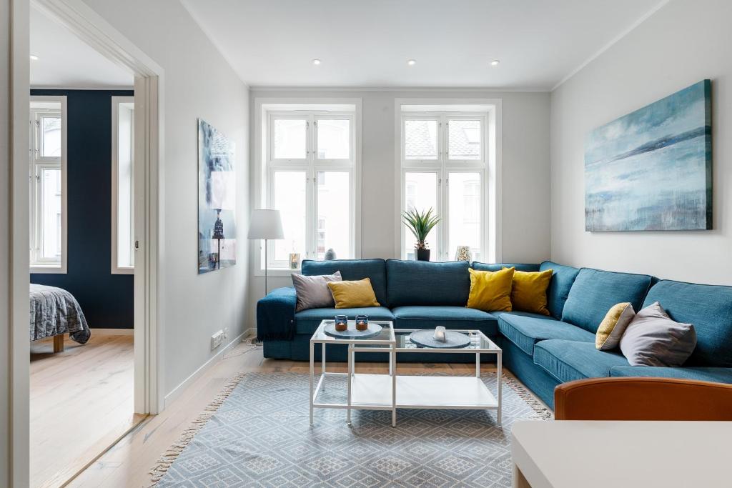 a living room with a blue couch and yellow pillows at Høyden Apartments in Bergen