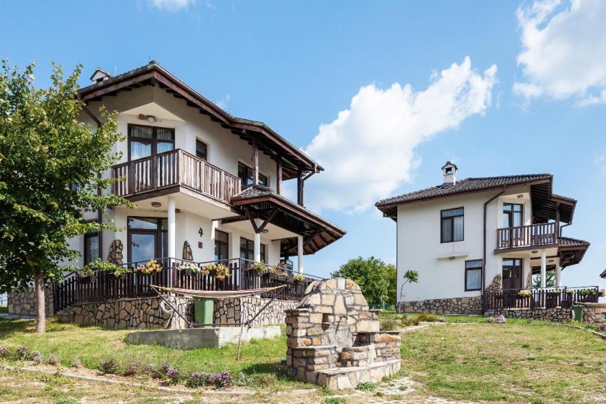 a large white house with balconies and a yard at Balkana Village in Kalaydzhii