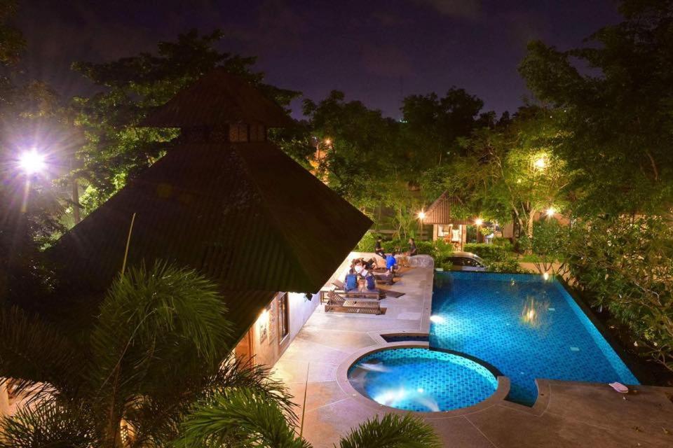 a swimming pool at night with people sitting around it at Chalicha Resort in Chumphon