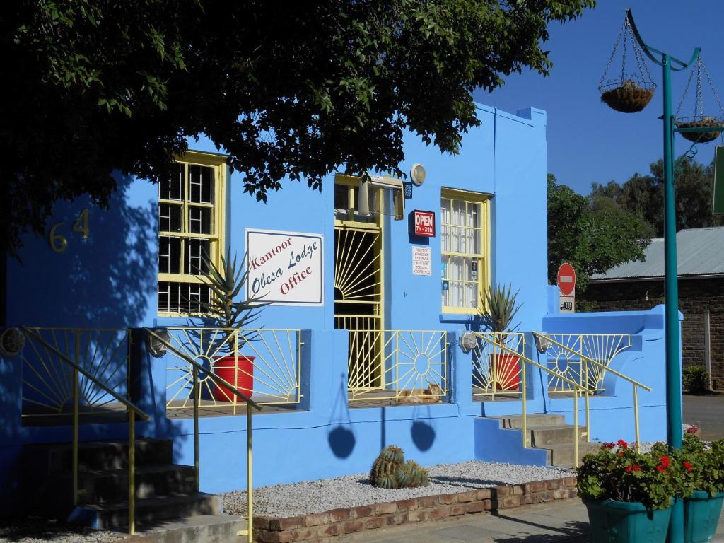 un bâtiment bleu avec portes et fenêtres jaunes dans l'établissement Obesa Lodge, à Graaff-Reinet