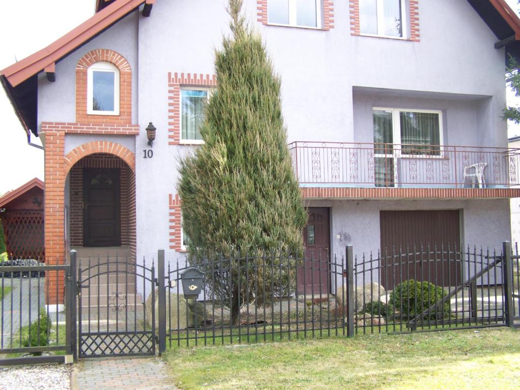een wit huis met een hek en een boom bij Cicha 10 Na górze in Ostróda