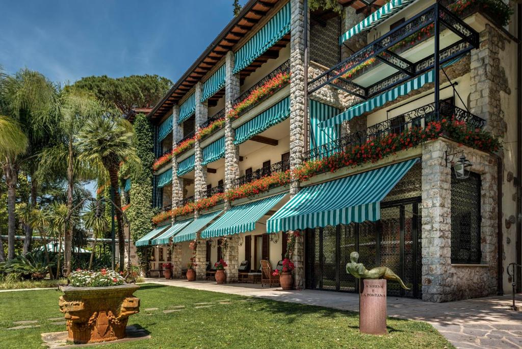 a building with green awnings and plants on it at Augustus Hotel & Resort in Forte dei Marmi