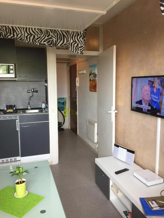 a room with a kitchen with a tv on the wall at Fréjus Studio in Fréjus