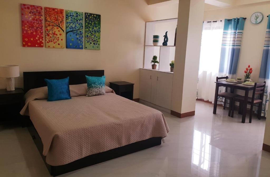 een slaapkamer met een bed met blauwe kussens en een tafel bij MS Residence Building in Lucban