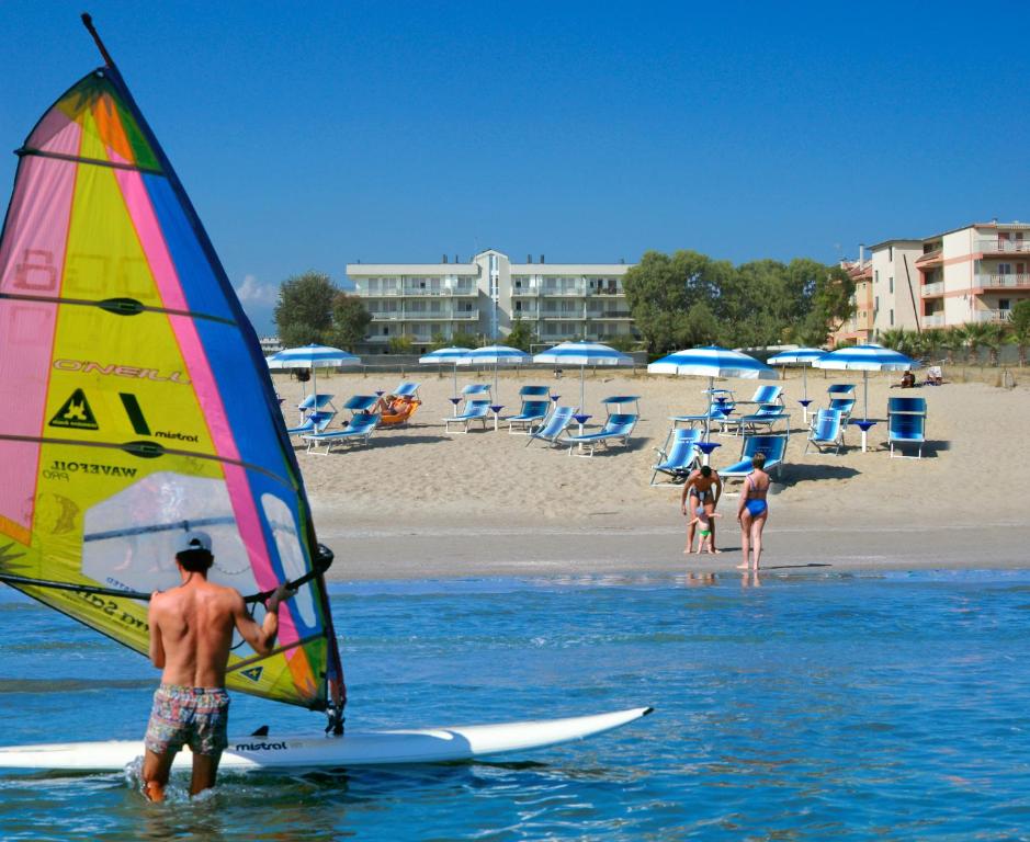聖貝內代托德爾特龍托的住宿－布勒沙迪瑪瑞住宿酒店，站在水面上,在冲浪板上摆帆的人