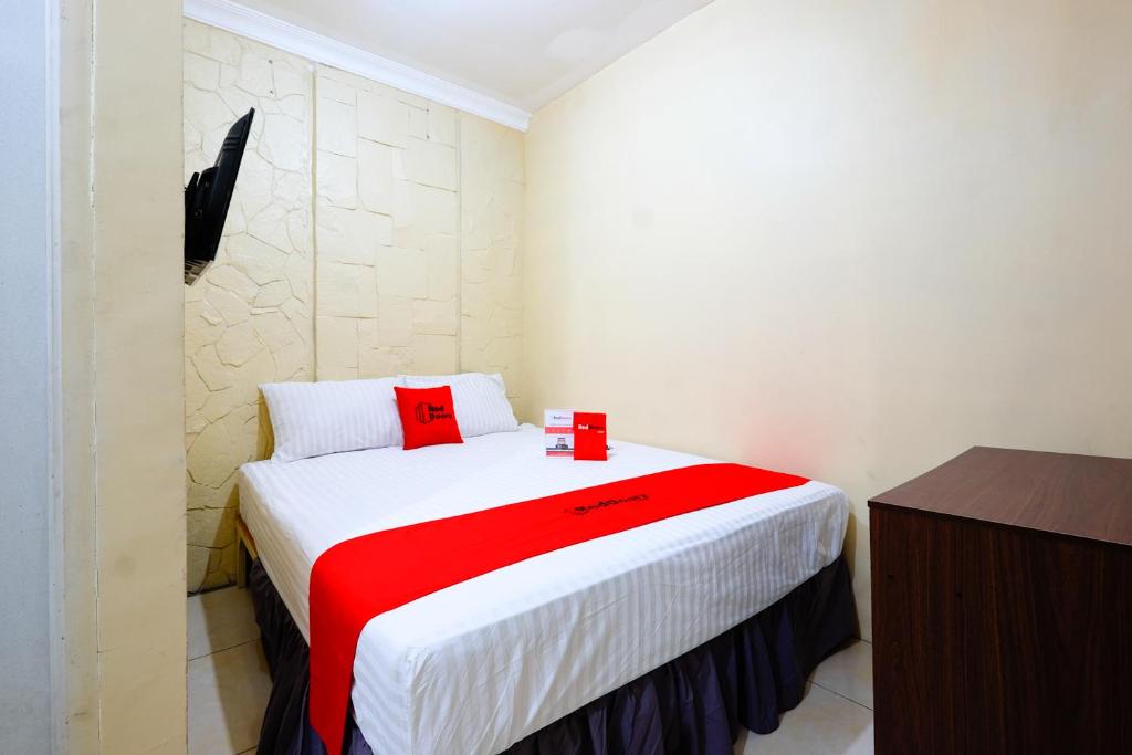 1 dormitorio con 1 cama grande con manta roja en RedDoorz @ Jalan Setiabudi Semarang en Semarang